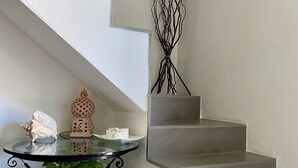A staircase with a modern design, a glass table with decorative items, and a potted plant. - The Sisters' house (Santo Stefano di Magra)
