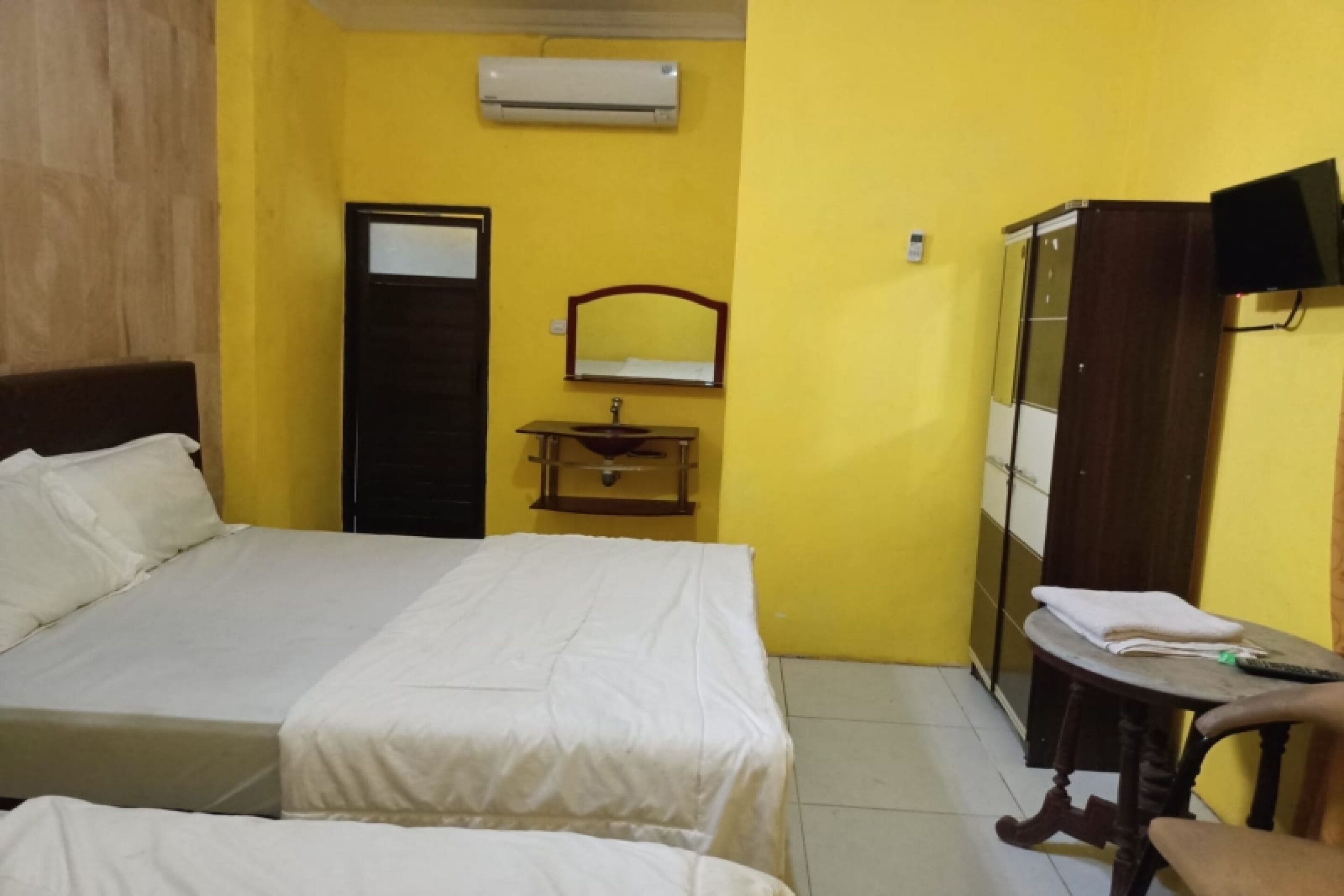 A hotel room with a bed, a bedside table with a lamp, a mirror, and a wardrobe.