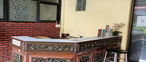 A reception desk with intricate carvings, a black stool, and a sign labeled "RECEPTION".