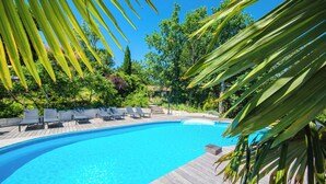 A swimming pool with wooden deck and lounge chairs, surrounded by lush greenery and trees. - Le Triangle D'or - Gite 80m2 - Piscine - Gaillac (Gaillac)
