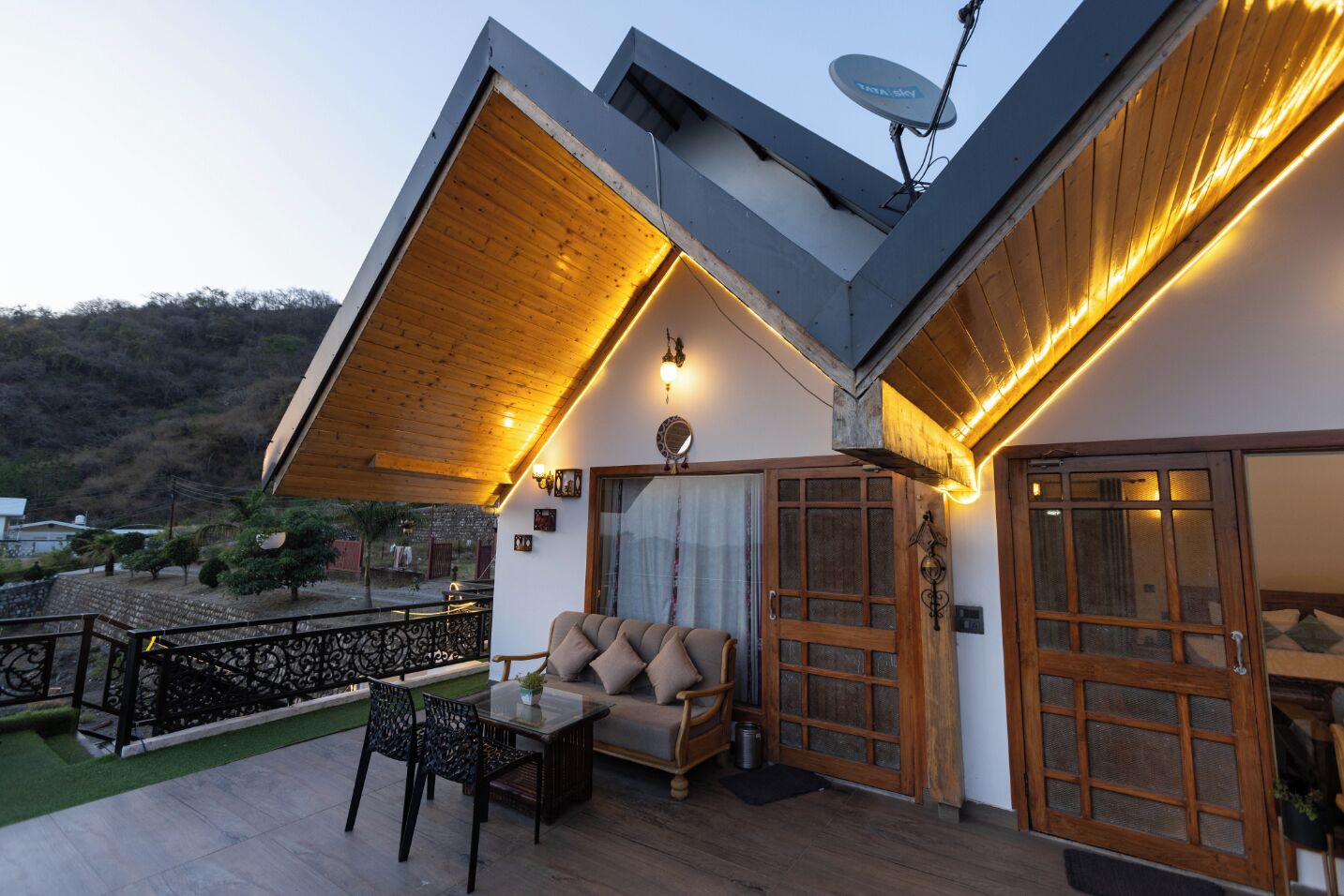 A modern house with a wooden deck, a sofa, and a dining table.