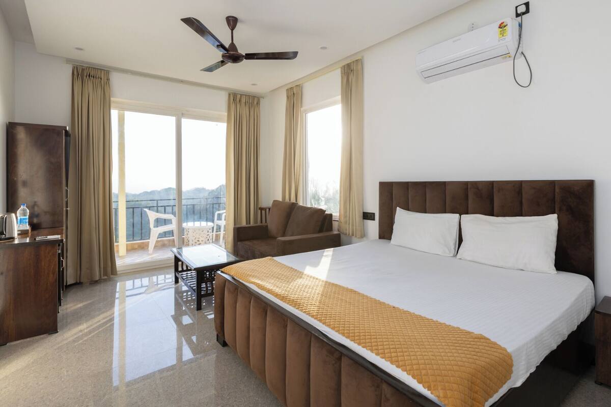 A hotel room with a bed, a desk, a chair, a ceiling fan, and an air conditioning unit.