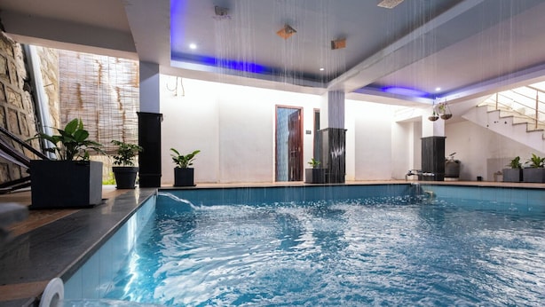 Una piscina amb jatos d'aigua, plantes en testos, una escala i un disseny interior modern.