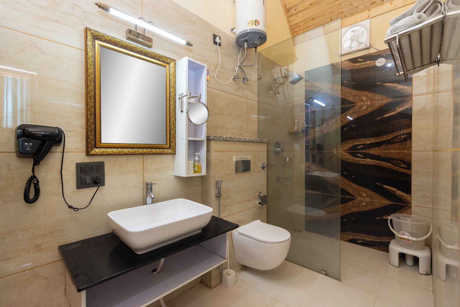 Un baño moderno con lavamanos blanco, cabina de ducha de vidrio y pared con diseño de mármol.
