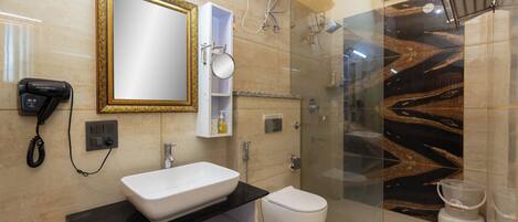 Un baño moderno con lavamanos blanco, cabina de ducha de vidrio y pared con diseño de mármol.
