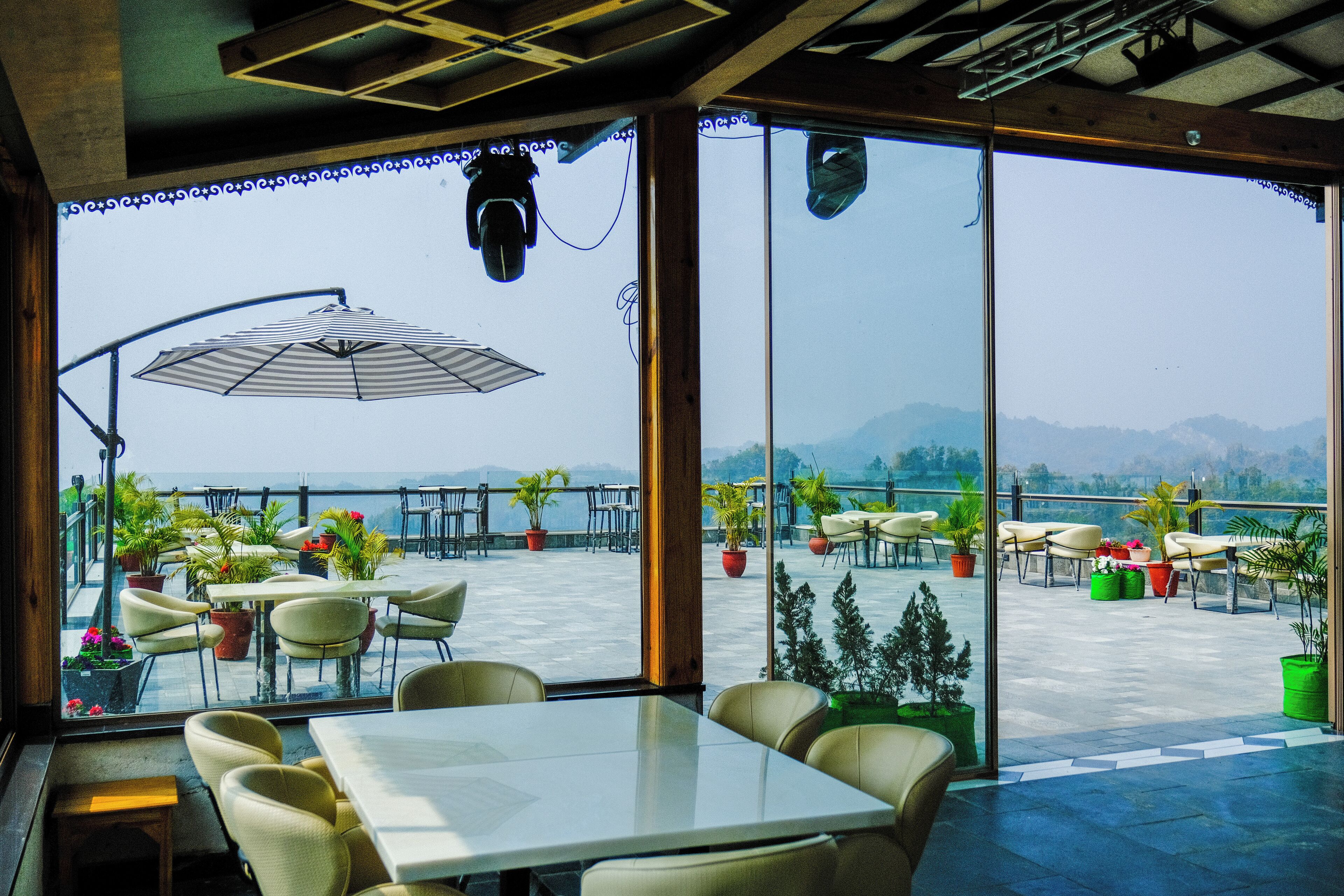 Une terrasse avec des tables et des chaises, des plantes en pot et une vue sur la mer.