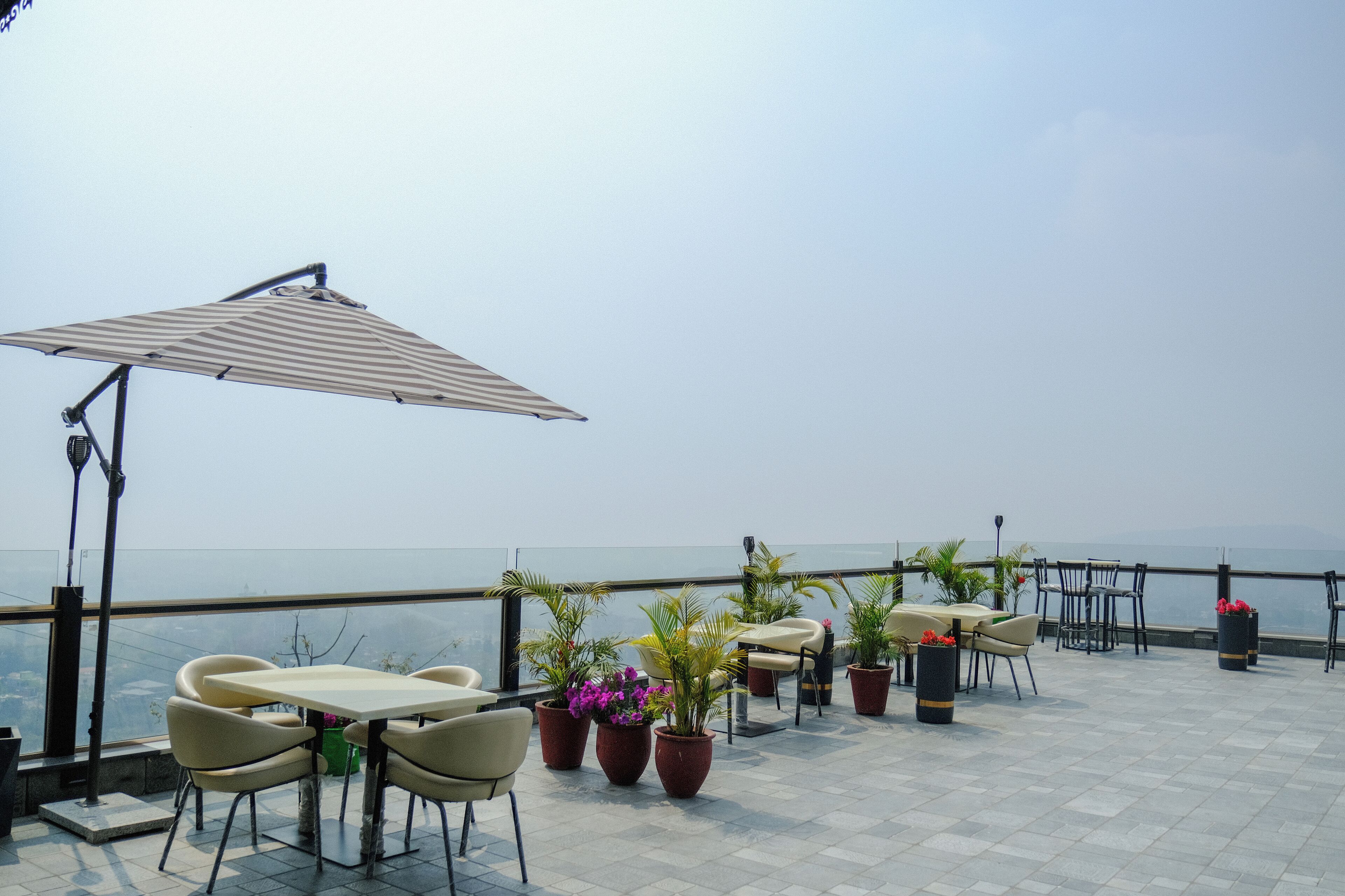 A terrace with outdoor seating, potted plants, and a view of the sea.