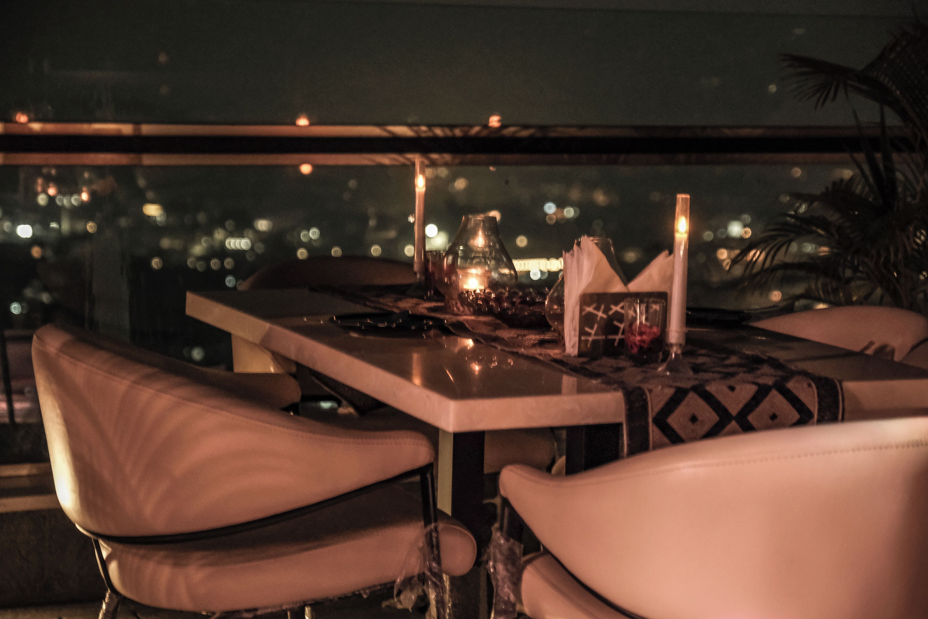 Une table dressée pour deux personnes, avec vue sur la ville, une bougie et une bouteille.