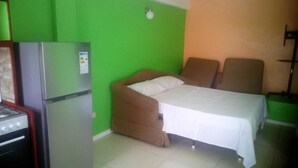 A small room with a bed, a chair, a refrigerator, and a stove. - Corinth Convinced Studio (Gros Islet)