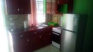 A kitchen with wooden cabinets, a gas stove, and a refrigerator. - Corinth Convinced Studio (Gros Islet)