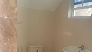 A small bathroom with a toilet, a sink, and a window. - Corinth Convinced Studio (Gros Islet)