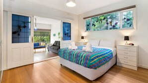 Un dormitorio con una cama grande, una mesita de noche, un aparador, un ventanal con un diseño de vitral y vistas a un balcón.