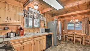 A wooden cabin kitchen with a wooden table, chairs, a refrigerator, a microwave, a toaster, and a sink. - Comfortable Mi-wuk Village Cabin: Hike & Ski! (Mi-Wuk Village)