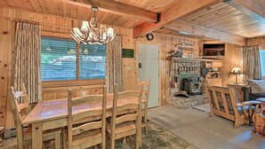 A wooden interior with a dining table, chairs, a chandelier, a fireplace, and a television. - Comfortable Mi-wuk Village Cabin: Hike & Ski! (Mi-Wuk Village)