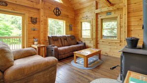 A cabin with wooden walls, a brown leather sofa, a wooden coffee table, and a wood-burning stove. - Londonderry Chalet w/ Deck, Fire Pit & Views! (Londonderry)