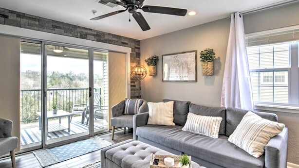 A modern living room with a grey sofa, a ceiling fan, and a balcony with a view. - Branson Retreat w/ Balcony & 18-hole Golf Course! (Branson)