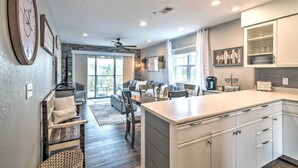 A modern kitchen with white cabinets, a large island, and a dining area with a sofa and chairs. - Branson Retreat w/ Balcony & 18-hole Golf Course! (Branson)