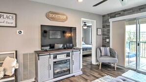 A modern living room with a fireplace, a television, and a seating area with a gray armchair and a sofa. - Branson Retreat w/ Balcony & 18-hole Golf Course! (Branson)