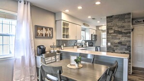 A modern kitchen with a central island, white cabinetry, and a stone accent wall. - Branson Retreat w/ Balcony & 18-hole Golf Course! (Branson)