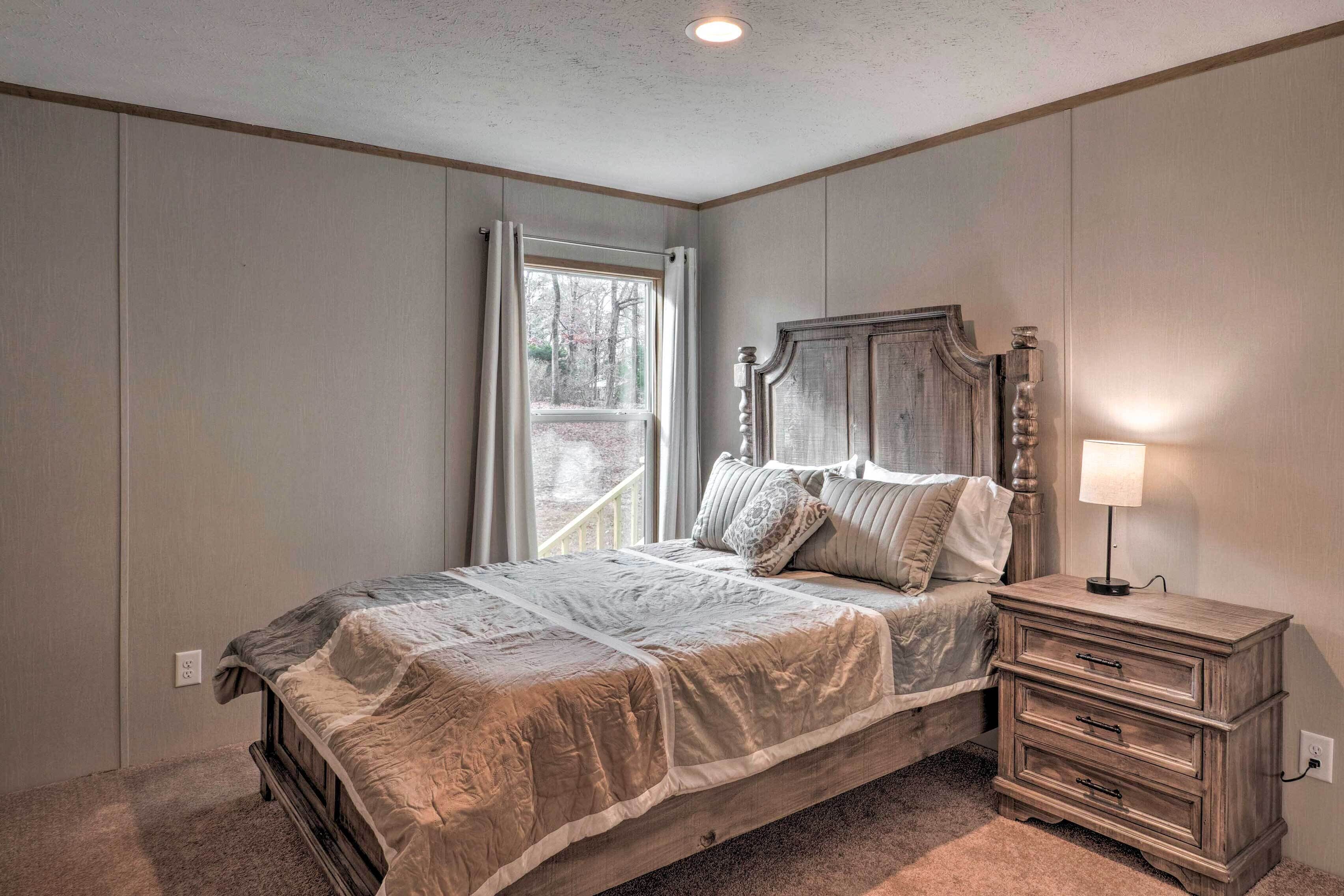 A bedroom with a bed, a nightstand, and a window with curtains.