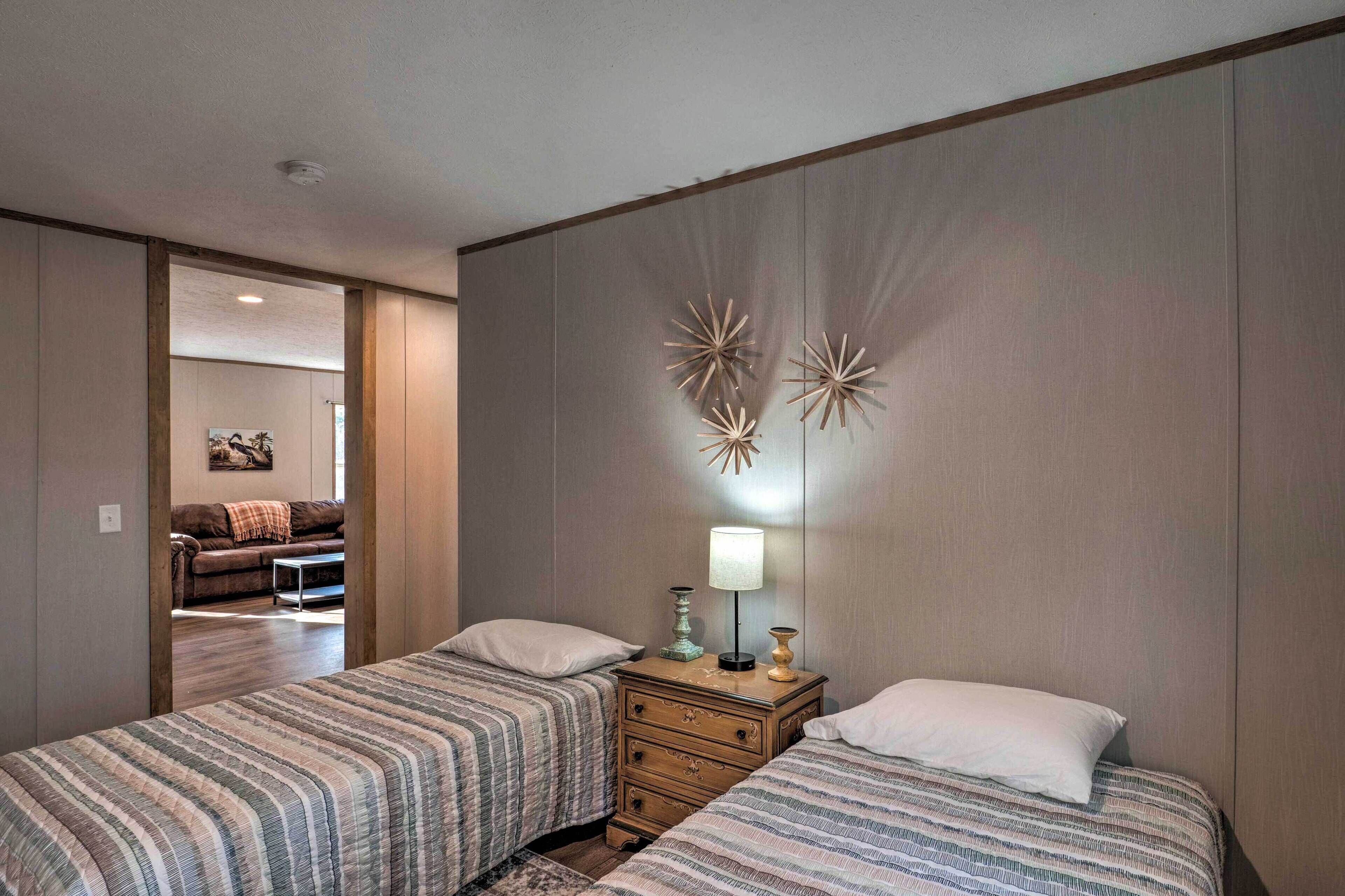 A bedroom with two beds, a nightstand, and a wall-mounted lamp.