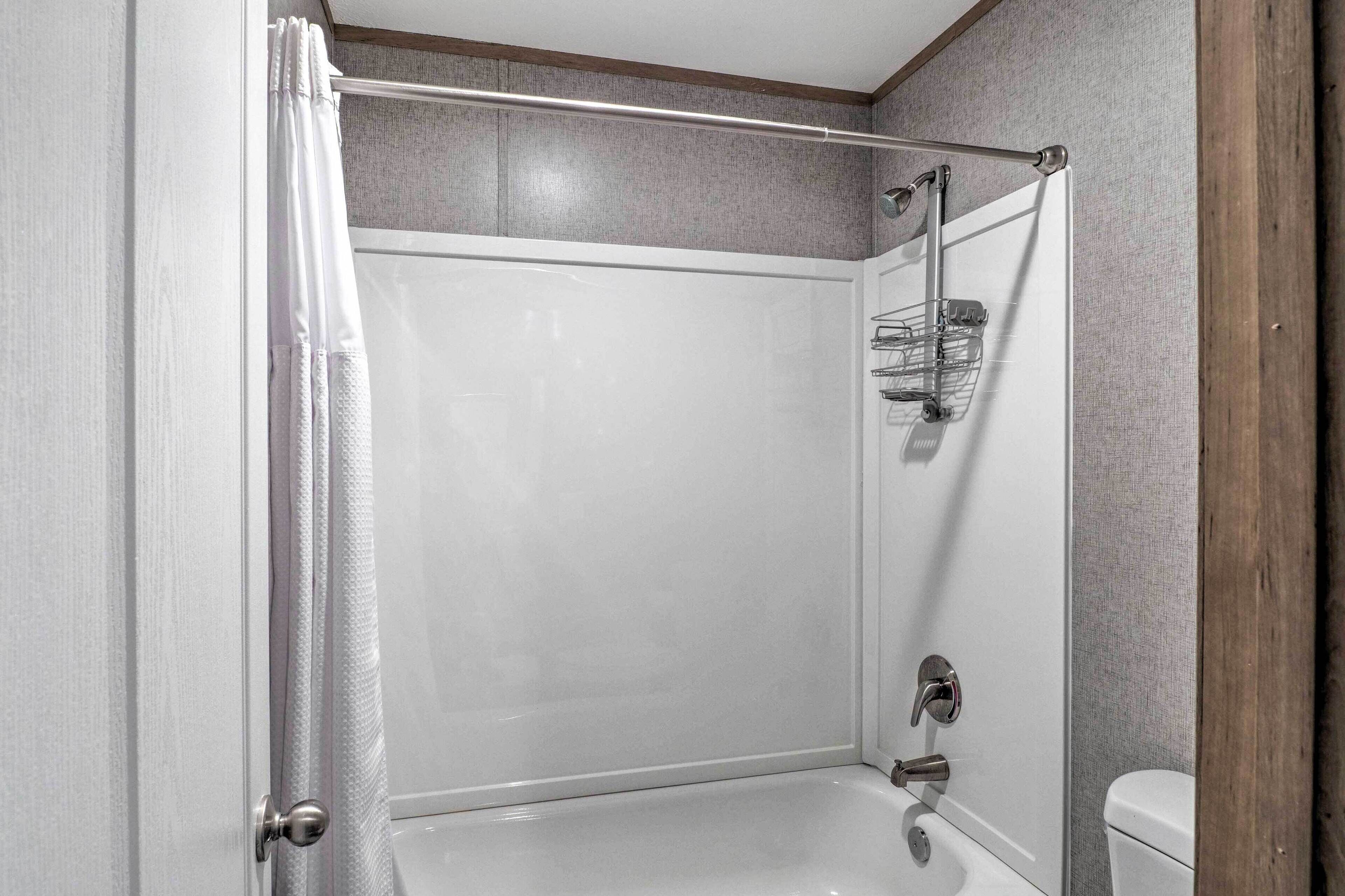 A modern bathroom with a glass shower enclosure, a white bathtub, and a toilet.