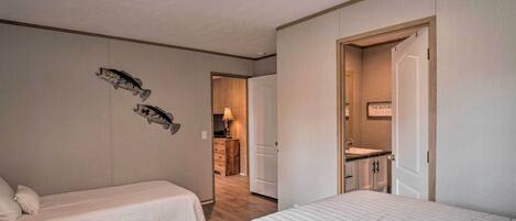 A hotel room with two beds, a bathroom, and a small kitchenette.