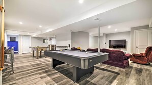 Un salon moderne avec une table de billard, des sièges confortables et un téléviseur.