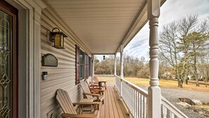 Une véranda en bois avec une balustrade, des sièges d’extérieur et une vue sur le paysage environnant.