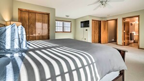 Une chambre à coucher avec un lit, un ventilateur de plafond, une fenêtre et un téléviseur fixé au mur.