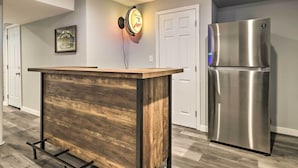 Une cuisine dotée d’un îlot central en bois, d’un réfrigérateur en acier inoxydable et d’un luminaire fixé au mur.