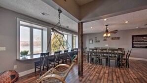A spacious dining area with a wooden table and chairs, a hanging swing chair, and large windows providing a view of the outdoors. - Dock & Hot Tub: Susquehanna River Retreat! (Pequea)