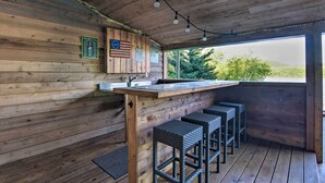 A wooden cabin interior with a bar area, wooden walls, and a view of greenery outside. - Dock & Hot Tub: Susquehanna River Retreat! (Pequea)