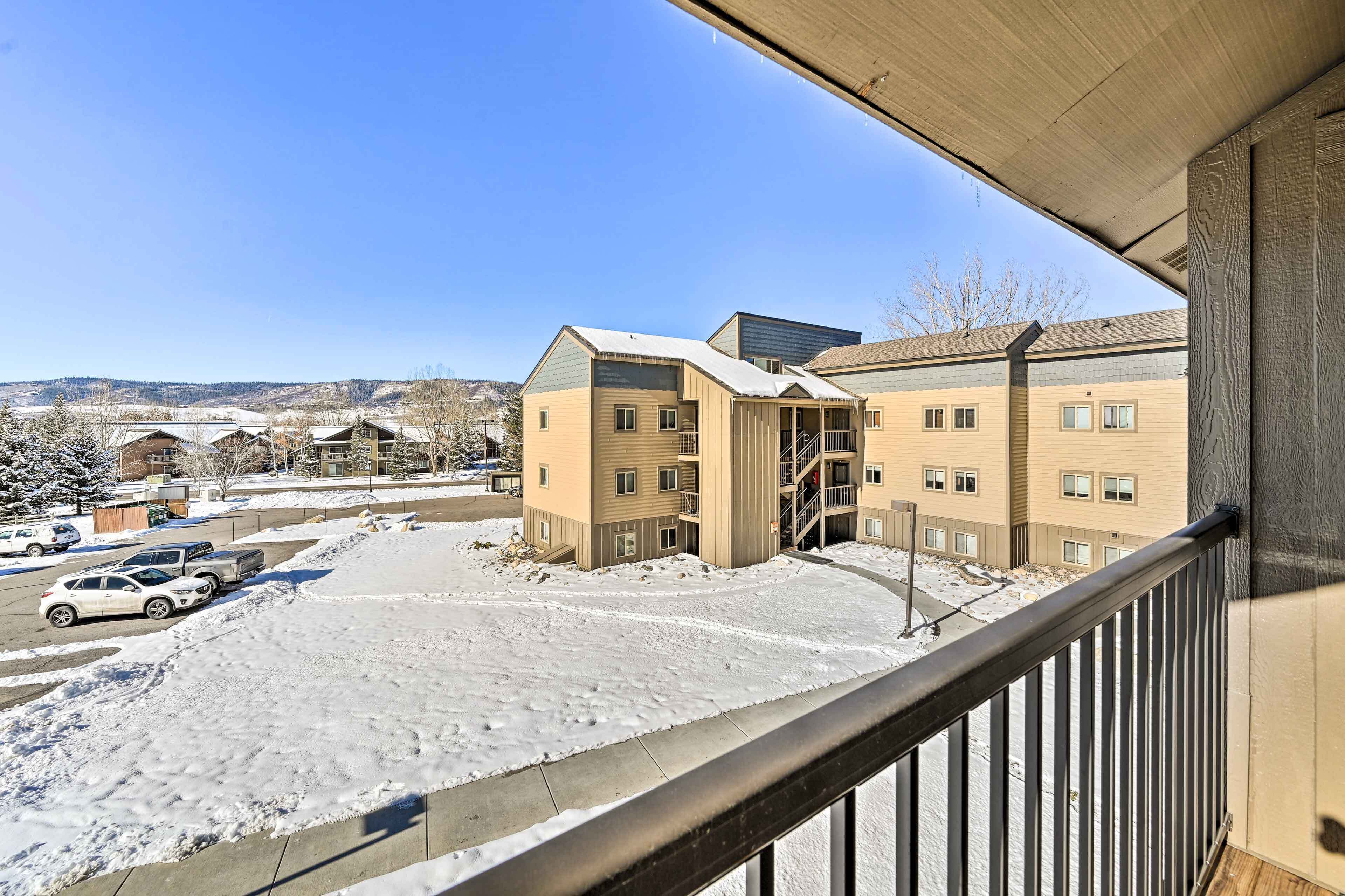A multi-story building with a snow-covered ground and a parking lot with cars.
