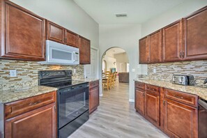 A kitchen with wooden cabinets, a microwave, a stove, and a toaster. - Family Getaway w/ Pool, Only 8 Mi to Disney! (Kissimmee)