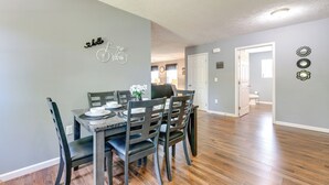 A dining area with a table set for four, a chair with a unique design, and a wall-mounted sign that reads "hello" with a bicycle graphic. - 2 Mi to Douglas Lake, Boat Ramp: White Pine Home! (White Pine)