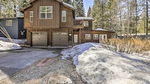 A two-story wooden cabin with a garage, surrounded by snow and trees. - 6 Mi to Lake Tahoe: Home w/ Hot Tub & Views! (South Lake Tahoe)