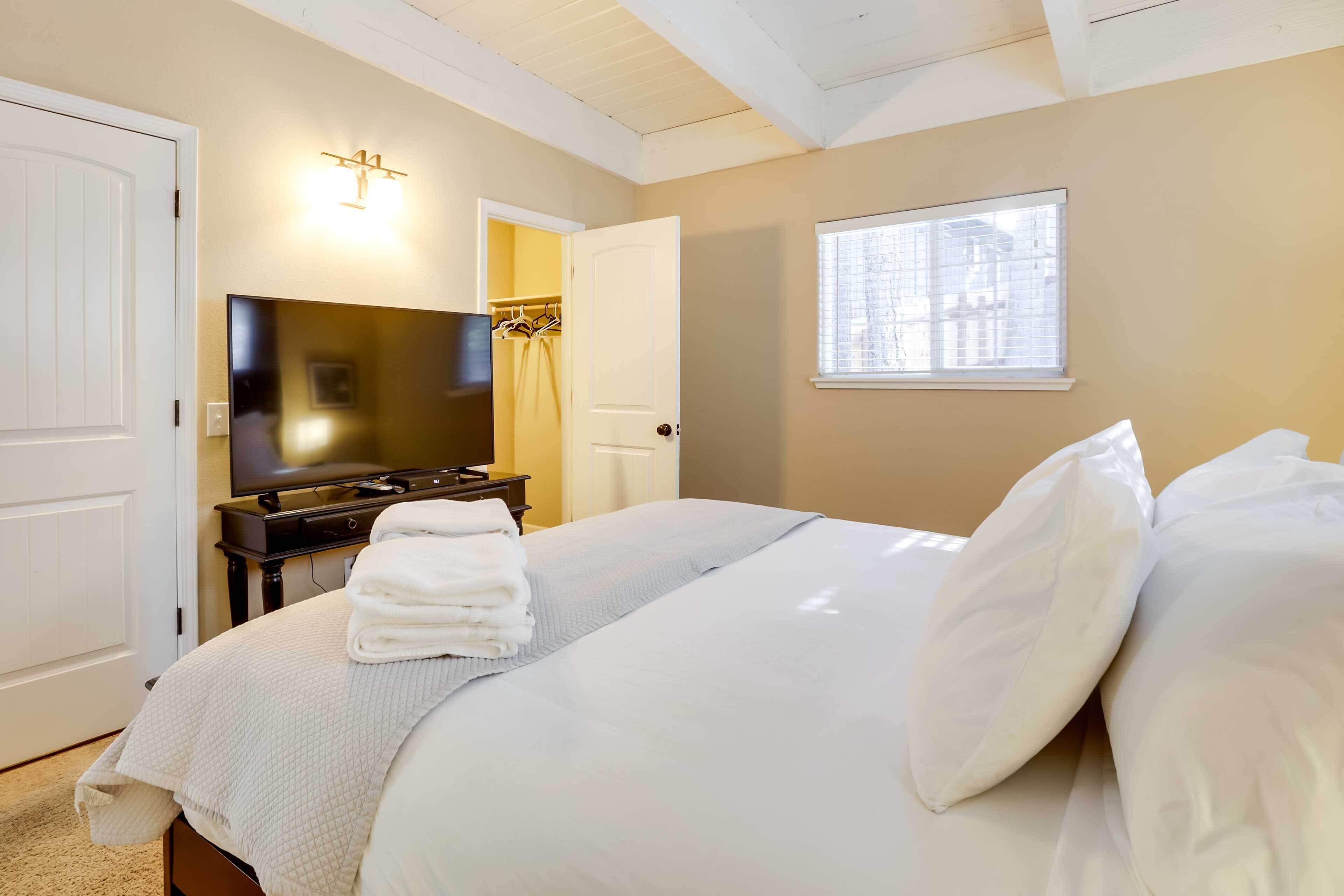 A hotel room with a bed, a television, a wardrobe, and a window with a view of buildings.