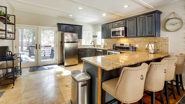 A modern kitchen with dark cabinets, a granite countertop, and a stainless steel refrigerator. - 6 Mi to Lake Tahoe: Home w/ Hot Tub & Views! (South Lake Tahoe)
