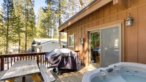 A wooden deck with a hot tub, a covered grill, and a sliding glass door leading to a covered patio area. - 6 Mi to Lake Tahoe: Home w/ Hot Tub & Views! (South Lake Tahoe)