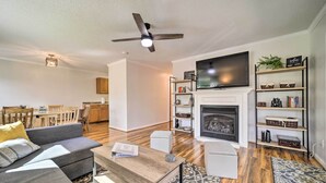A modern living room with a sofa, coffee table, fireplace, television, and bookshelves. - 'smoky Mountain Solace' Home in Maggie Valley (Maggie Valley)