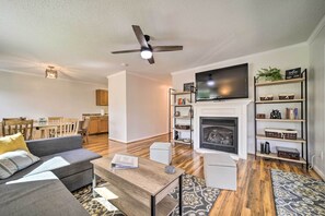 Uma sala de estar moderna com sofá, mesa de centro, lareira, televisão e estantes.
