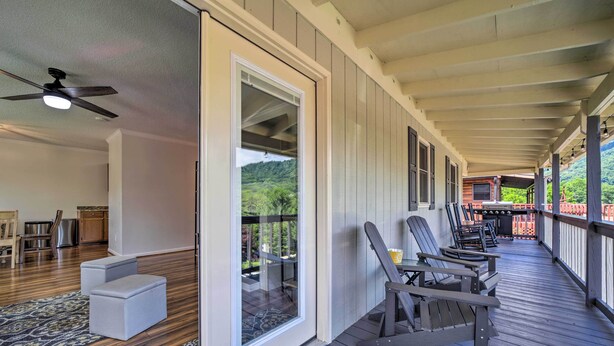 A covered porch with wooden flooring, a ceiling fan, and a view of a mountainous landscape. - 'smoky Mountain Solace' Home in Maggie Valley (Maggie Valley)
