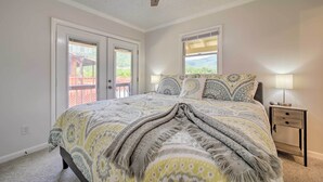 A bedroom with a bed, two windows, a ceiling fan, and a nightstand with a lamp. - 'smoky Mountain Solace' Home in Maggie Valley (Maggie Valley)