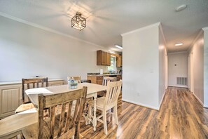 A dining area with a wooden table and chairs, a kitchen in the background, and a hallway with wooden flooring. - 'smoky Mountain Solace' Home in Maggie Valley (Maggie Valley)