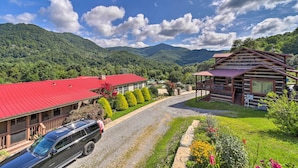 A cabin with a red roof, a covered porch, and a gravel driveway. - 'smoky Mountain Solace' Home in Maggie Valley (Maggie Valley)