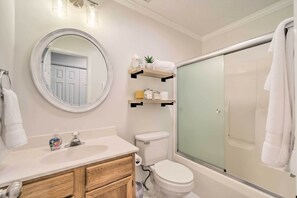 A bathroom with a white sink, wooden cabinets, a toilet, and a glass-enclosed shower. - 'smoky Mountain Solace' Home in Maggie Valley (Maggie Valley)