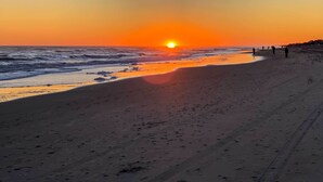 A beach at sunset with a clear sky, calm sea, and footprints on the sand. - Emerald Isle Condo w/ Direct Access to Ocean! (Emerald Isle)
