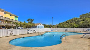 A swimming pool with a curved design, surrounded by a white fence, and adjacent to a building with multiple balconies. - Emerald Isle Condo w/ Direct Access to Ocean! (Emerald Isle)