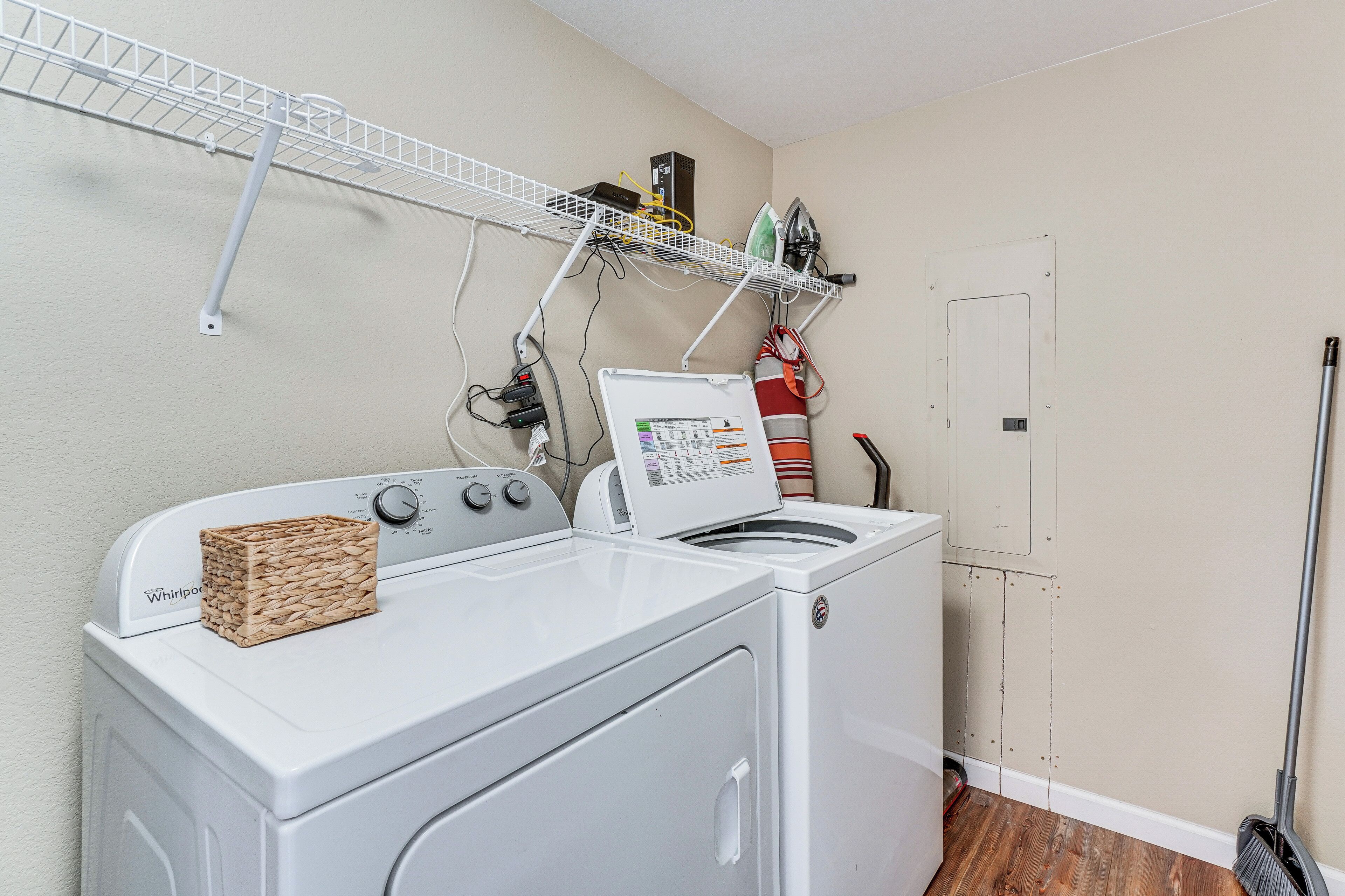 Un espace dédié à la lessive, comprenant un lave-linge, un étendoir et un balai-serpillière.